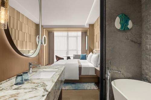 a hotel room with a bed and a tub and a sink at The Westin Yichang in Yichang