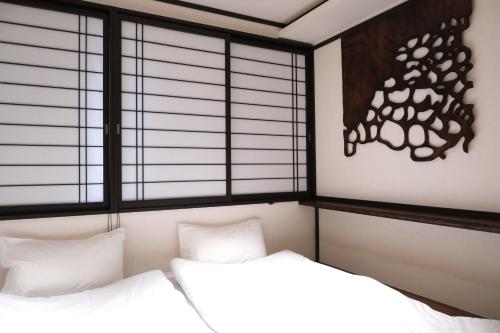 two beds in a room with two windows at 北川秋叶原 羽田机场直达 秋叶原站步行4分钟和风民宿 适合家庭和情侣入住 Poka Stay Akihabara in Tokyo