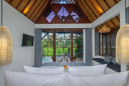 a living room with a white couch and a large window at Bara Villa by GenuineHost in Tegalalang