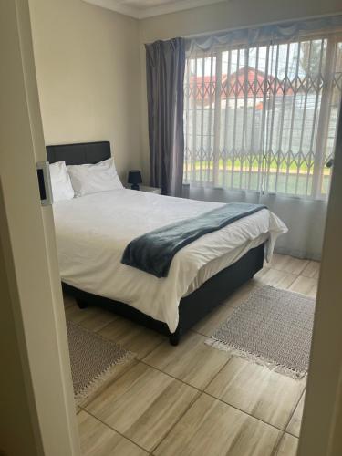 a bedroom with a bed and a large window at Centurion Family House in Centurion