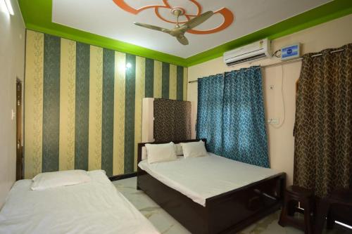 a bedroom with two beds and a ceiling fan at Sabri Palace Ayodhya in Ayodhya