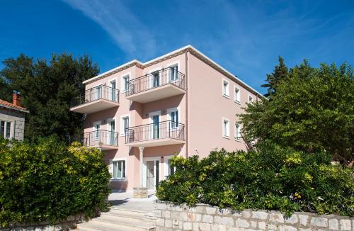 un edificio rosa con balcones y árboles en Maistra Select Srebreno Villas, en Mlini