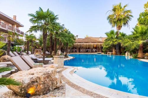 a swimming pool with chairs and palm trees in a resort at Achtis Hotel in Afitos