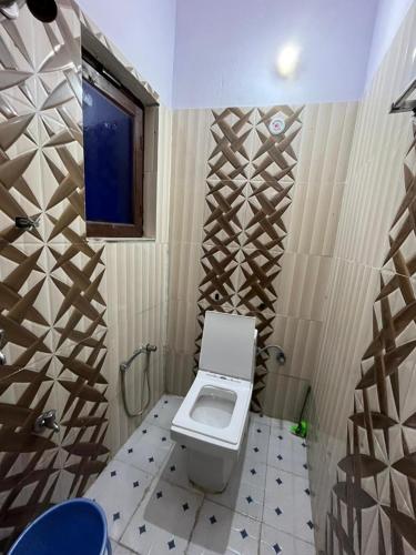 a small bathroom with a toilet and a window at Chandarshila hike homestay in Ukhimath