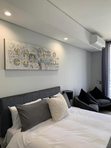 a bedroom with a white bed and a couch at Ellipse Luxurious Tamarind Green Studio Experience in Midrand