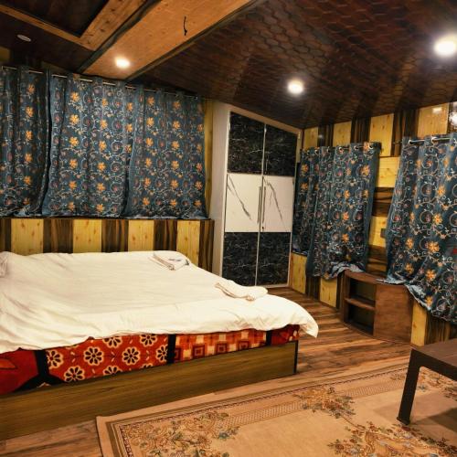 a bedroom with a bed and blue curtains at Id villa cottage in Tangmarg