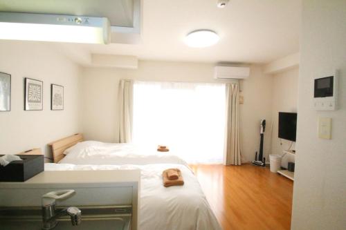 a bedroom with two beds and a large window at オンブラージュ704号室-無料駐車場付き-繁華街まで徒歩圏内-南向きで明るいワンルーム in Kumamoto