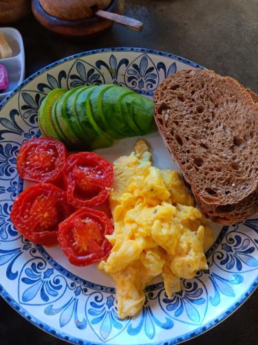 a plate of food with eggs and tomatoes and bread at Uma Mupu in Gianyar