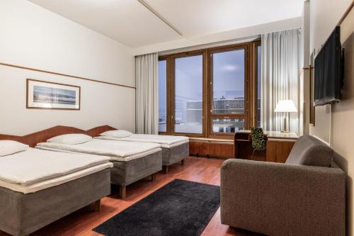 a hotel room with three beds and a couch and a window at Scandic Polar in Rovaniemi