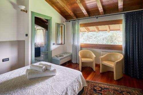 a bedroom with a bed and two chairs and a window at Dream's hill in San Pietro di Feletto