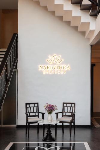 a table with two chairs and a vase with flowers at Narinthra Heritage in Chiang Mai