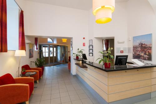 un vestíbulo de un hospital con sillas naranjas y un mostrador en Exe City Park Hotel en Praga