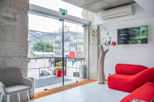 a living room with a red couch and a large window at Oca Ribeira do Porto Hotel in Porto