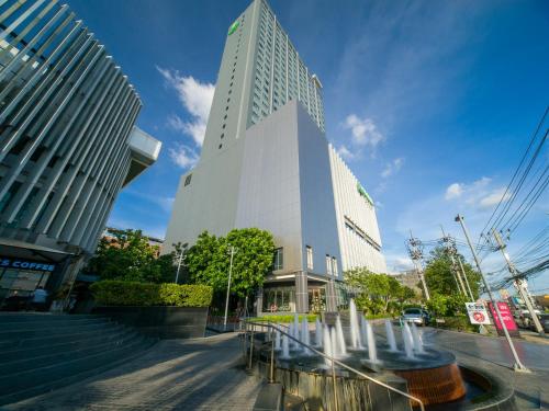a tall building with a fountain in front of it at Holiday Inn & Suites Rayong City Centre by IHG in Rayong