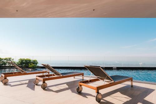 three lounge chairs sitting on the edge of a swimming pool at Holiday Inn & Suites Rayong City Centre by IHG in Rayong