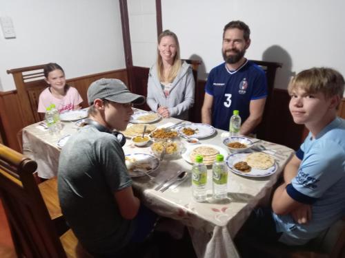 een groep mensen die rond een tafel zitten en eten bij Ruchi House in Nuwara Eliya