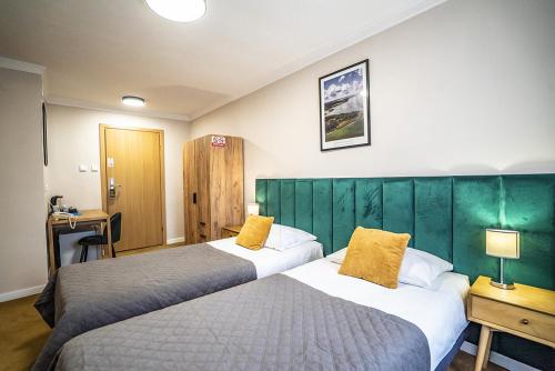 a hotel room with two beds with yellow pillows at Hotel Ognisty Ptak in Węgorzewo