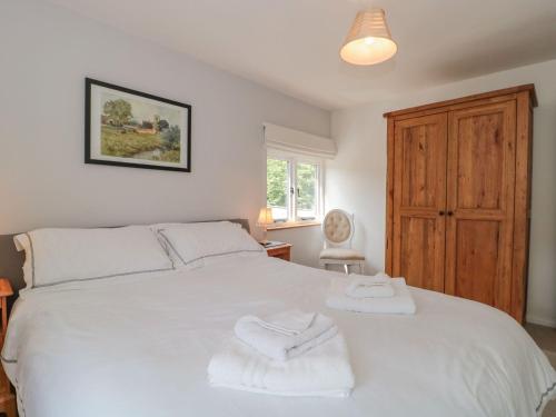 a bedroom with a white bed with towels on it at Greenham Rise in Chiselborough
