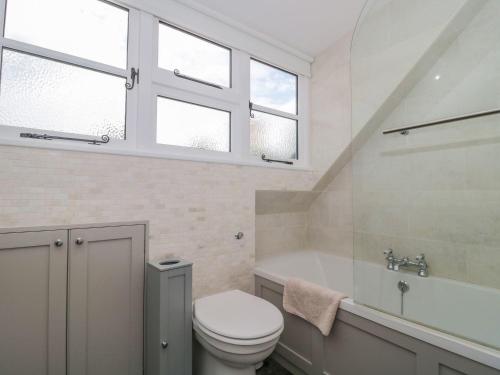 a bathroom with a toilet and a tub and windows at Greenham Rise in Chiselborough
