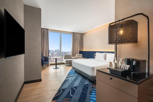a hotel room with a bed and a television at Novotel Jakarta Pulo Mas in Jakarta
