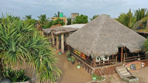 atropical building with a straw roof and palm trees at Thats why beach hotel in Trincomalee