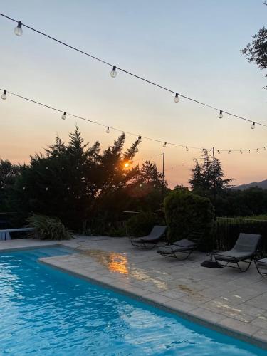 a pool with chairs and a sunset in the background at Les Tournillayres in Bédoin