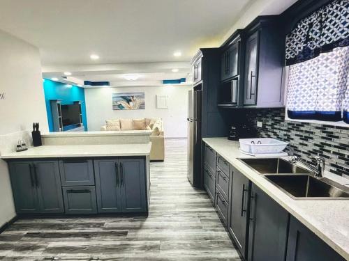 a kitchen with dark blue cabinets and a living room at Tobago Tropical Hideaway in Lowlands