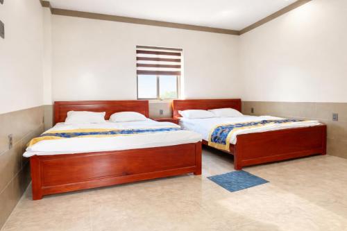 two beds sitting in a room with a window at Khách Sạn - Cà Phê Dinh Cô in Long Hai