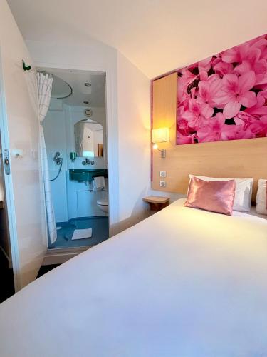 a bedroom with a large white bed and a bathroom at Fasthotel Orleans Zénith in Orléans