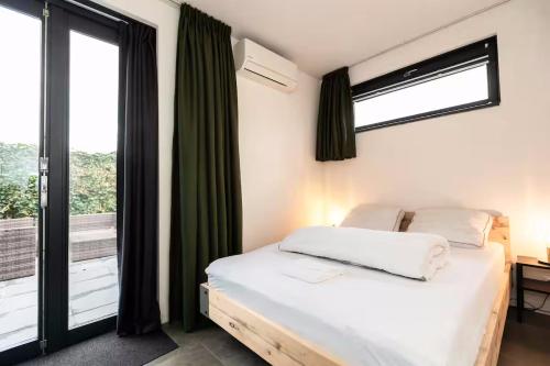 a bedroom with two beds and a large window at Luxe wellness woning met prive buitensauna in Ermelo