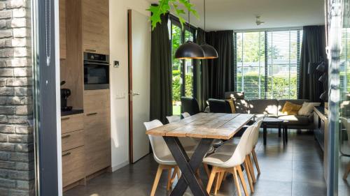 a kitchen and dining room with a wooden table and chairs at Luxe wellness woning met prive buitensauna in Ermelo