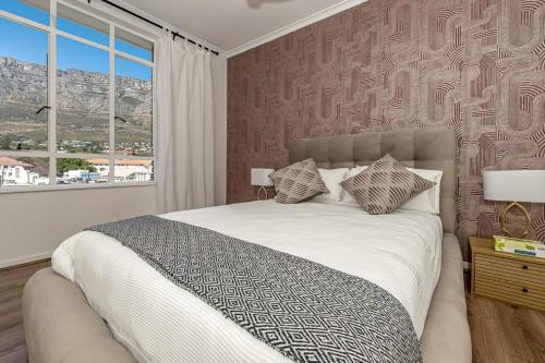 a bedroom with a large bed with a large window at Table Mountain Views - Stylish Gardens Apartment in Cape Town