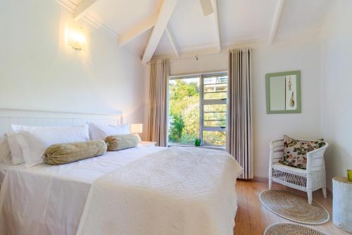 a bedroom with a large white bed and a window at The Sullies in Morganʼs Bay
