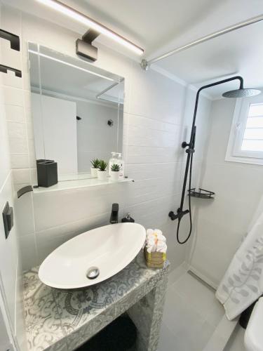 a white bathroom with a sink and a mirror at Sadin apartment in Neos Marmaras