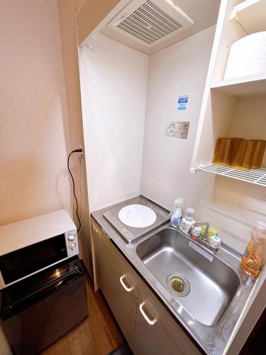 a small kitchen with a sink and a microwave at クオリティハイツ101号室 in Tokyo