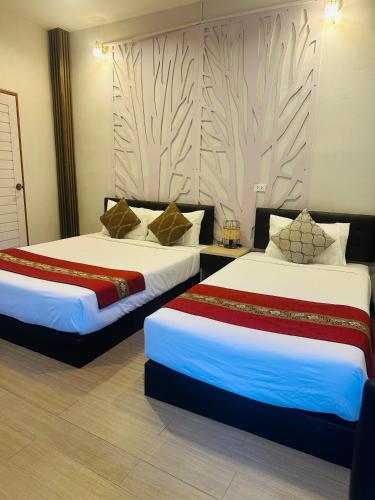 two beds in a hotel room with two at V Rich วีริชเพลส ร้อยเอ็ด in Ban Non Muang