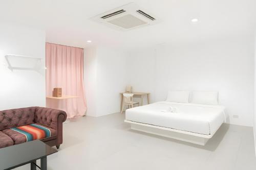 a white bedroom with a bed and a couch at XX Mitr Inn Sukhumvit Soi 2 - มิตร อินน์ สุขุมวิท ซอย 2 BTS Nana in Bang Kapi