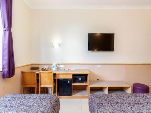 a room with a desk and a tv on the wall at Eurotraveller Hotel - Premier - Tower Bridge in London