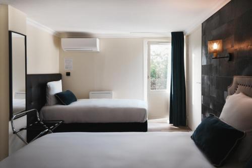 een hotelkamer met twee bedden en een raam bij Brit Hotel Confort Orly Morangis in Morangis