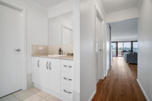 a kitchen with white cabinets and a hallway at Long Island Retreat - Rosella in Murray Bridge