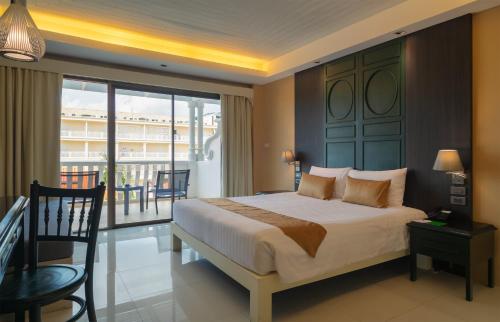 a bedroom with a bed and a balcony at The Old Phuket - Karon Beach Resort in Karon Beach