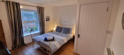 a small bedroom with a bed and a window at Sage Cottage Ventnor in Ventnor