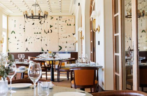 een restaurant met tafels en stoelen en een kroonluchter bij Hôtel Le Provençal - Rénové en 2025 - Bord de Mer in Hyères