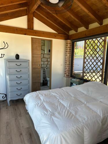 a bedroom with a white bed and a wooden ceiling at Le clos des Oiseaux in Itzac