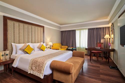a hotel room with a large bed and a desk at Hotel Swosti Premium Bhubaneswar in Bhubaneshwar