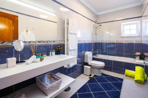 a blue tiled bathroom with a sink and a toilet at Villa Tranberg Suites in Ferreiras