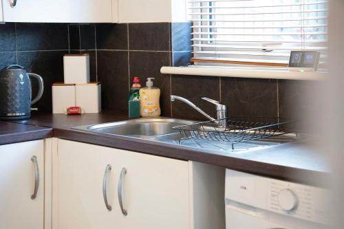 a kitchen sink with a dish drying rack next to it at Stylish 3BR House - Sleeps 5 - Free Parking in Ferryhill