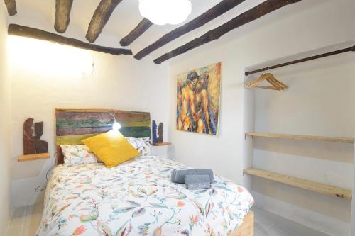 a bedroom with a bed and a painting on the wall at The Tile House in Güéjar-Sierra