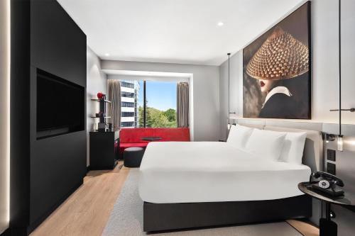 a bedroom with a white bed and a tv at Radisson RED Auckland in Auckland