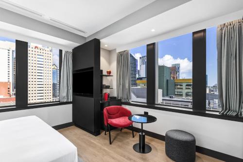 a hotel room with a bed and a red chair at Radisson RED Auckland in Auckland